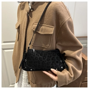 Detail of black leopard embossed shoulder bag with delicate bow and silver bottom studs