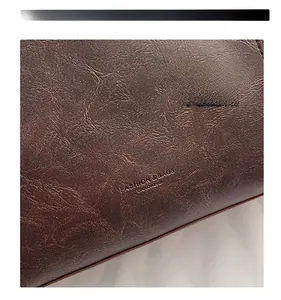 Detailansicht der dunkelbraunen Lederstruktur mit eingeprägtem Fashion-Schriftzug