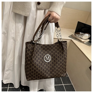 Detail der braunen Tragetasche mit M-Muster, Vintage-Stil und Metallkettenriemen