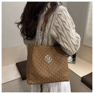 Brown tote bag with M-pattern print showing real-life size and shoulder fit on model