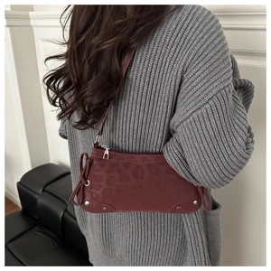 Detail of burgundy crescent bag with embossed leopard print and silver rivet accents