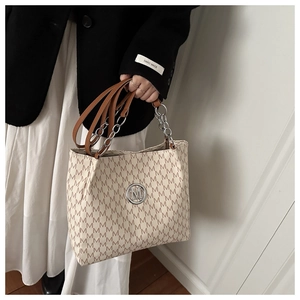 Detail der weichen Ledertasche mit M-Muster und silbernem Kettenhenkel