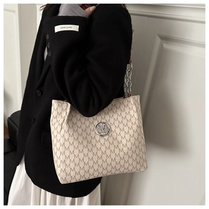 Detail der beigen Tragetasche mit M-Muster, Metallschnalle und Kettenriemen für Damen