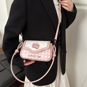 Pink apple-themed checkered crossbody bag with polka dot flap and bow detail on a model