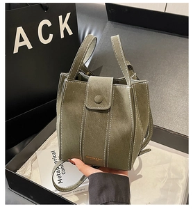 Detail view of olive green textured leather bucket bag with contrast white stitching in box
