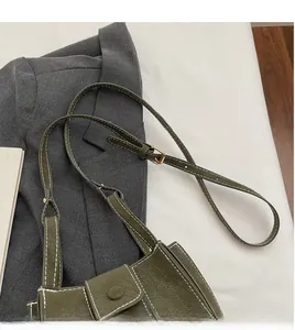 Detail of olive green leather bucket bag with white contrast stitching and gold buckle
