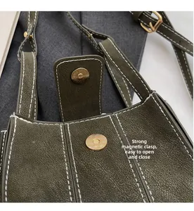 Close-up of the magnetic closure and white contrast stitching on a green textured bag