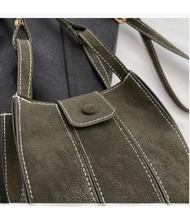 Detail of dark olive green bucket bag with contrast stitching and pebbled leather texture