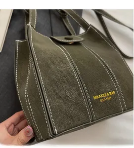 Detail of dark green bucket bag showing high-quality leather texture and white stitching