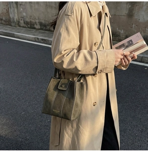 Close-up of olive green bucket bag with white stitching detail and gold stamped logo