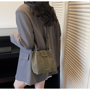 Detail of dark green suede tote bag with white contrast stitching and gold logo