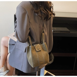 Detail of olive green bucket bag with white contrast stitching and branded bottom logo