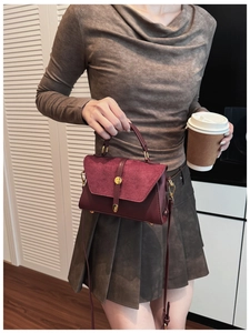Dettaglio borsa bordeaux opaca con serratura dorata e contrasto di texture pelle e camoscio