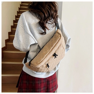 Detail of checkered texture and black drawstring accents on a beige crossbody bag