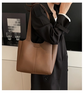 Detail of dark brown leather tote bag with vertical stitching and magnetic closure