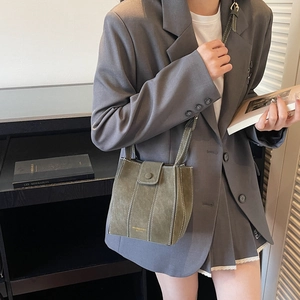Olive green bucket bag with contrast stitching held by model in professional suit