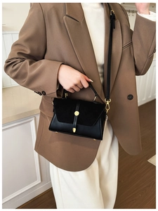 Elegante borsa a mano patchwork nera con dettagli dorati indossata da una modella