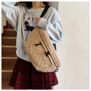 Detail of checkered crossbody bag with woven texture and black adjustable nylon strap