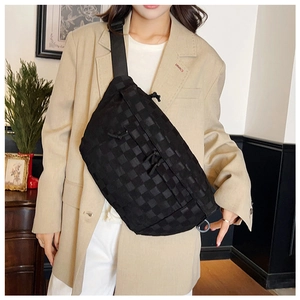 Detail of black checkered crossbody bag showing woven texture and adjustable strap