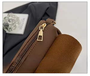 Detailed close-up of smooth gold metal zipper and stitching on brown leather tote bag