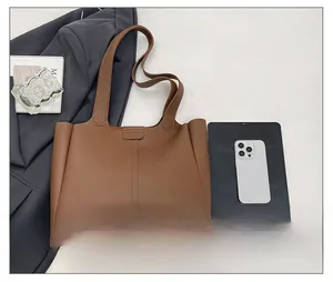 Brown leather tote bag detail with large capacity next to laptop and grey blazer