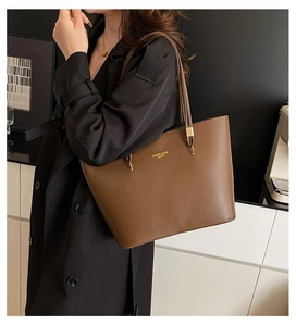 Brown leather tote bag side view showing large capacity and shoulder straps on a model