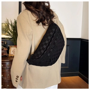 Detail of black checkered crossbody bag with adjustable strap and textured finish