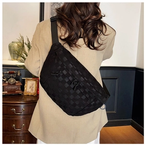 Close-up of black woven chest bag texture and crescent design on a beige blazer model