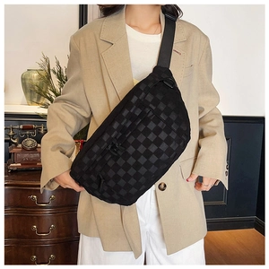 Close-up of black checkered texture on cross-body bag worn by a model in interior setting