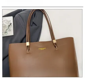 Detail of brown leather tote bag with gold D-rings and a stylish fashion magazine layout