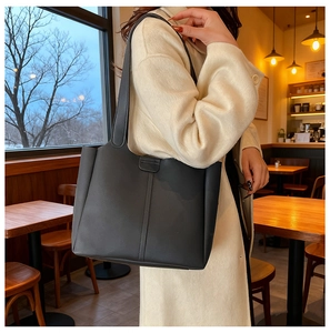 Detail of minimalist black matte leather tote bag with vertical decorative stitching