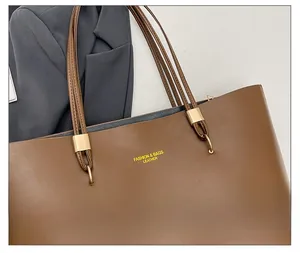 Close-up of golden hardware and smooth brown leather on a casual tote shoulder bag