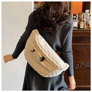 Detail of off-white woven texture chest bag with black drawstring and metal ring