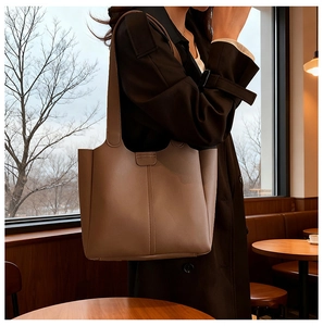 Detail of a brown leather tote bag showing high-quality stitching and wide shoulder straps