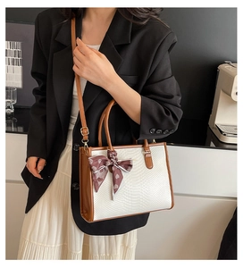 Detail of white snakeskin embossed tote with brown handles and a heart print silk scarf