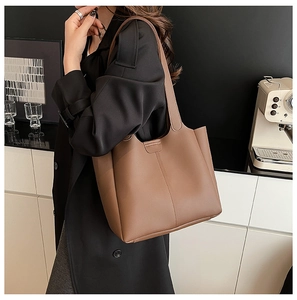 Detail of a brown leather tote bag with vertical stitching and semicircular clasp detail