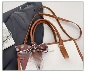 Detailed macro of white crocodile-embossed tote bag with heart-print silk scarf and gold text
