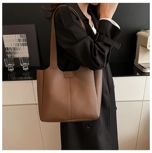 Sac fourre-tout en cuir marron pour femme porté par un mannequin dans un décor moderne