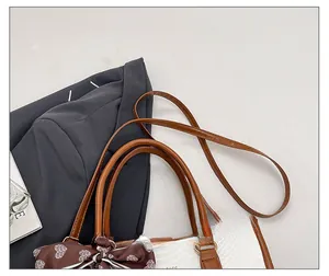 Detail of adjustable leather strap and silk scarf charm on textured handbag