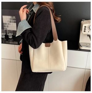 Detailed view of cream PU leather tote bag with brown straps in a lifestyle setting