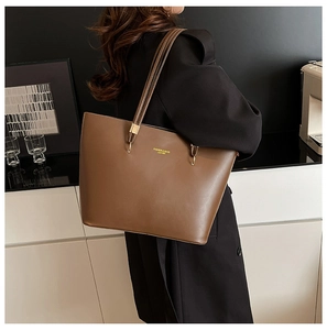 Close-up of deep brown leather tote bag with gold logo and long shoulder straps