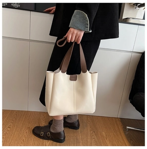 Détail du sac fourre-tout crème avec poignées marron et surpiqûres verticales