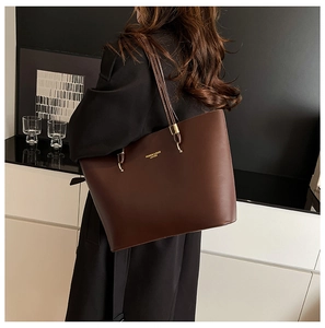 Close-up of deep brown leather tote bag with gold metal hardware and embossed lettering
