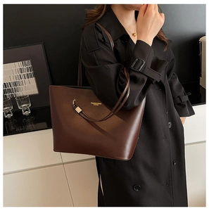 Detail of dark brown faux leather tote bag with gold lettering and metallic hardware