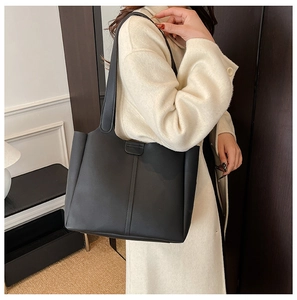 Vue latérale détaillée d'un cabas en cuir noir mat minimaliste porté par un mannequin