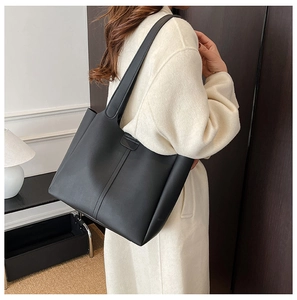 Gros plan d'un sac cabas minimaliste en cuir noir avec coutures verticales et anses