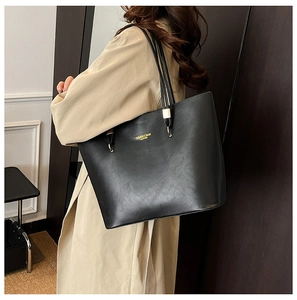 Detail view of black PU leather tote bag with gold lettering shown on a model