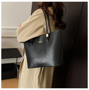 Detail view of large black tote bag with gold lettering and metallic hardware buckle