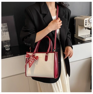 Detail of faux snake skin tote with contrast wine red handles and silk scarf accent