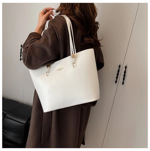 Detail of white PU leather tote bag with gold lettering shown on a shoulder